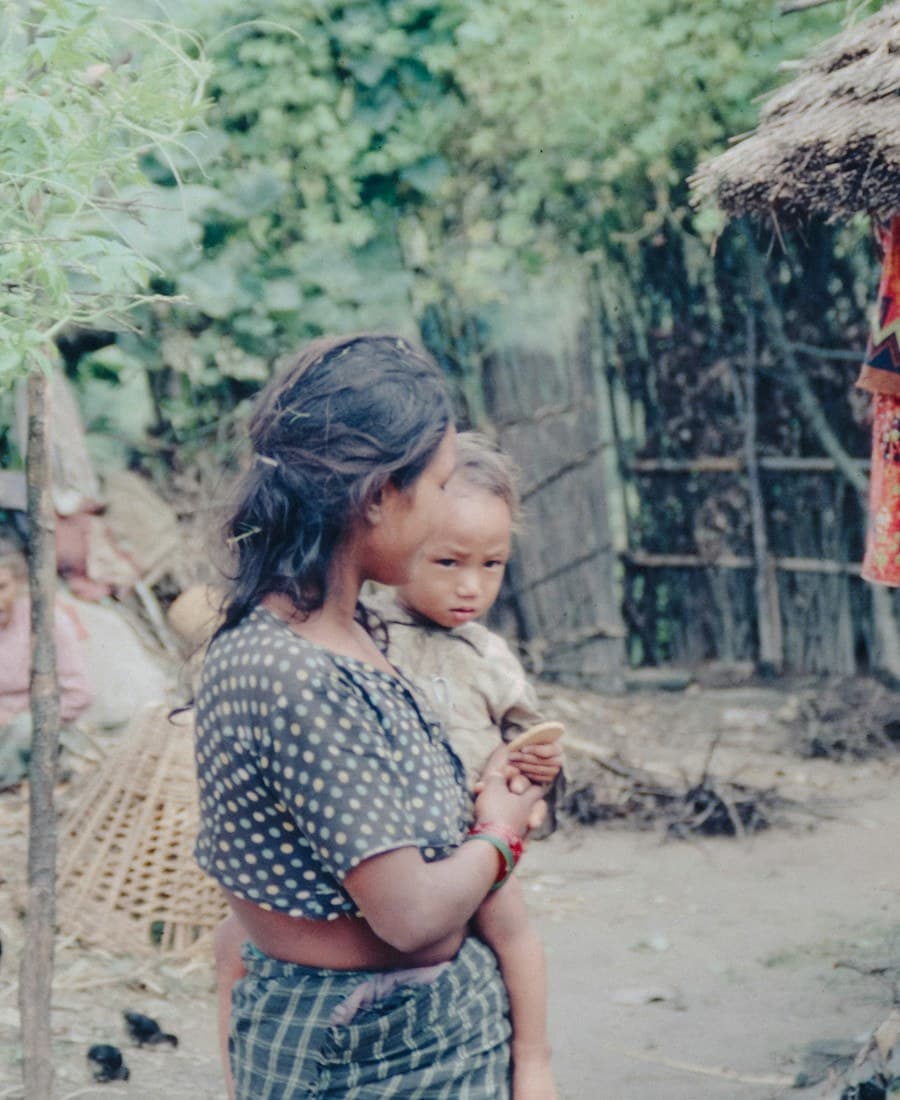 A mother and child outside a rural home