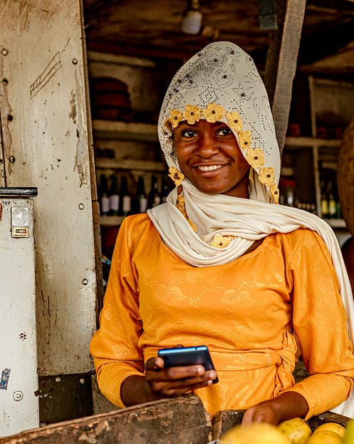 A market trader in Northern Nigeria using a mobile phone at her stall